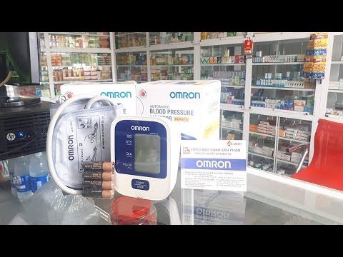 Máy đo huyết áp Omron HEM-8712 khi được mở hộp, cùng với sách hướng dẫn sử dụng.